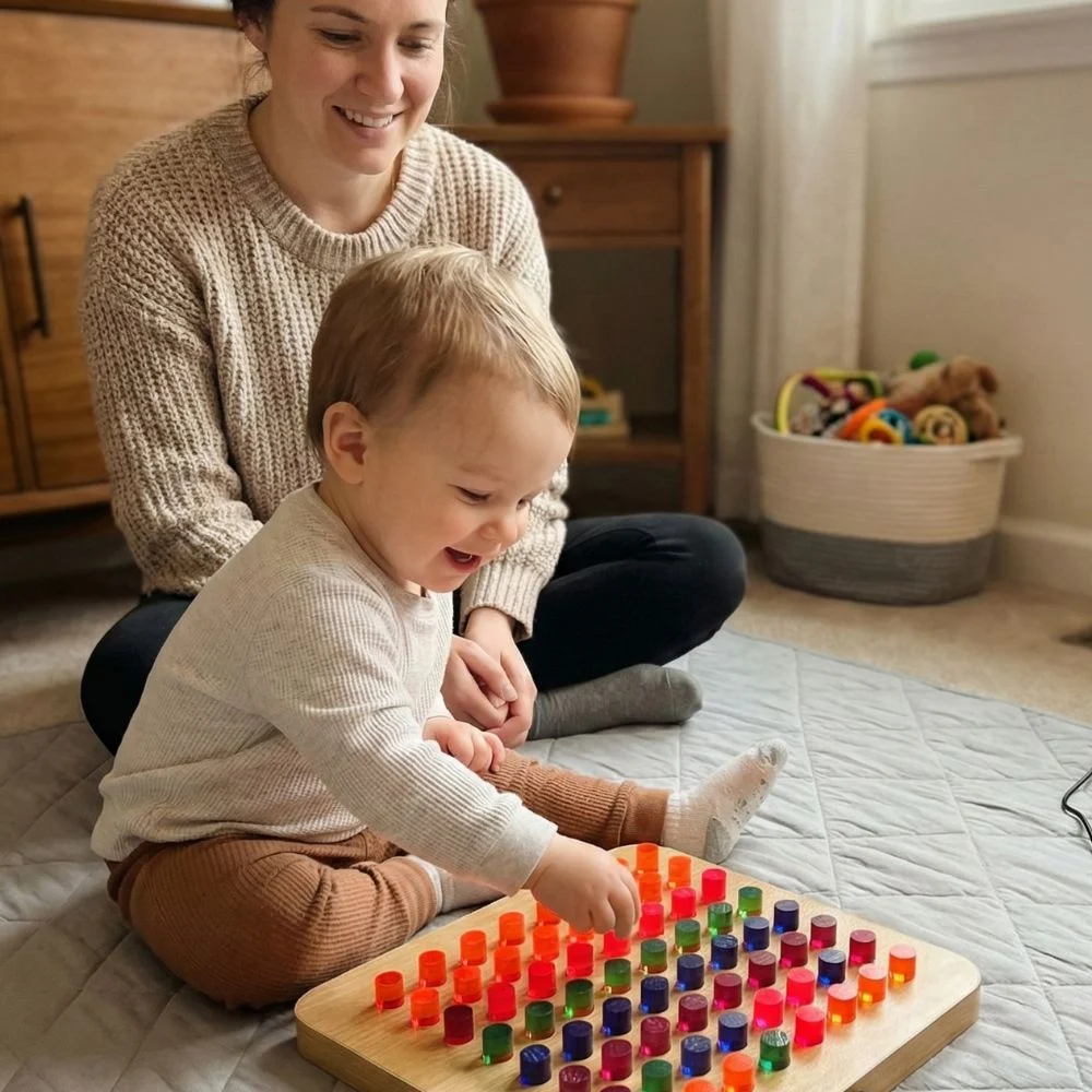Child playing with a light-up sensory peg board placing acrylic color pegs