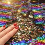 Close-up of rainbow-to-gold reversible flip sequin fabric texture